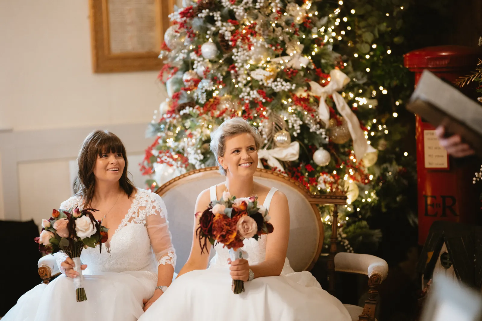 The couple seated beside the Christmas tree