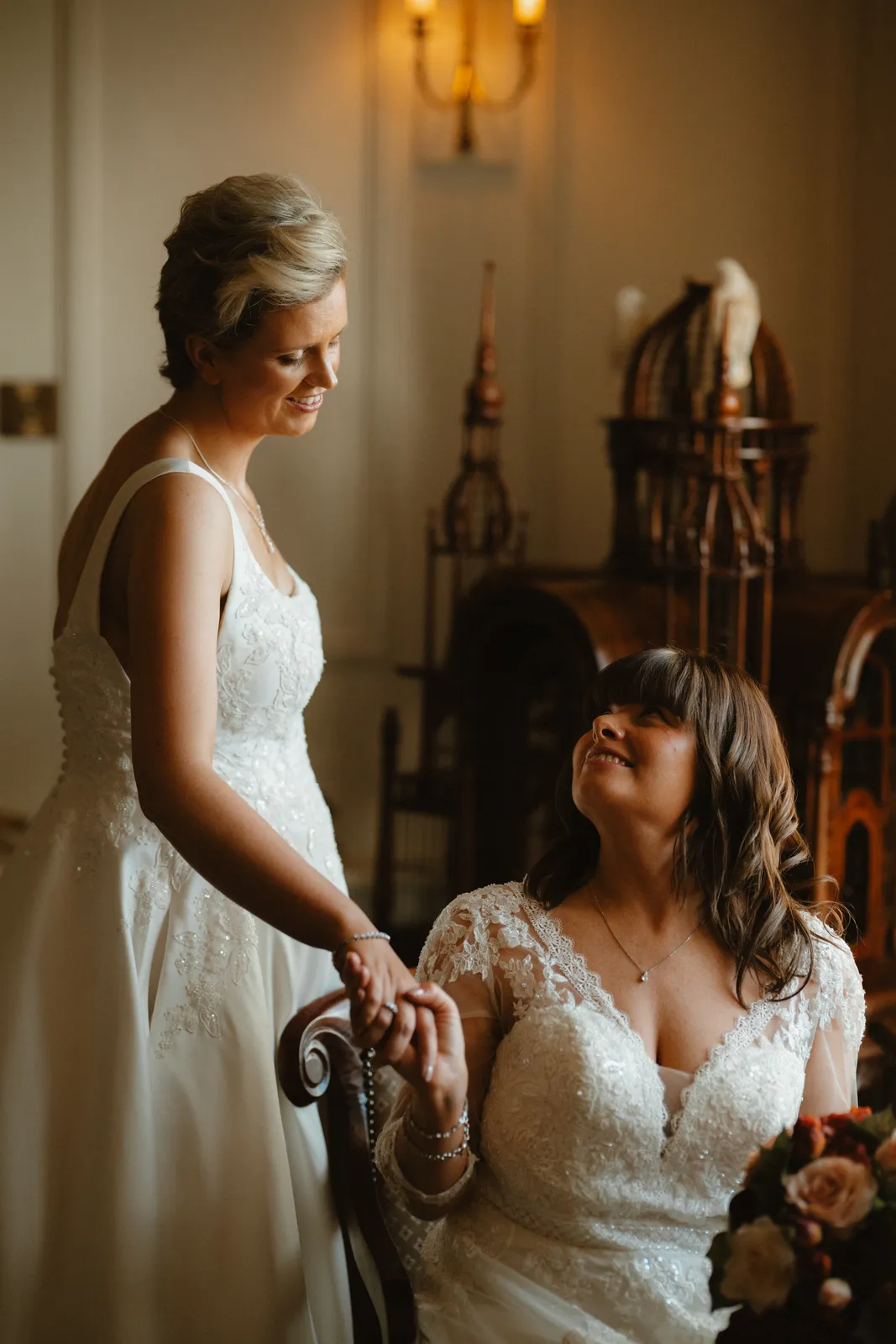 The couple hold hands beside a chair