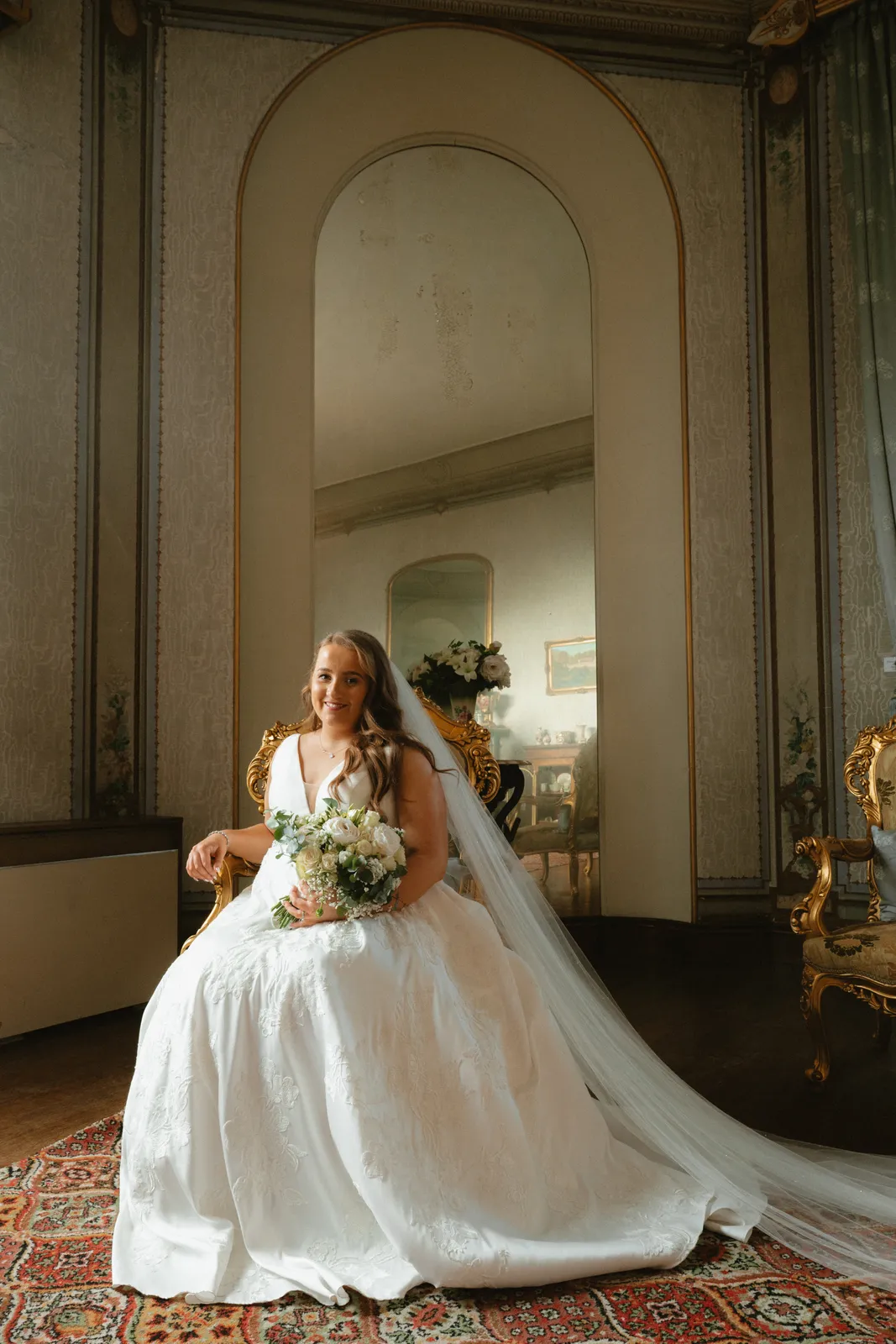 Leah seated beneath a tall mirror