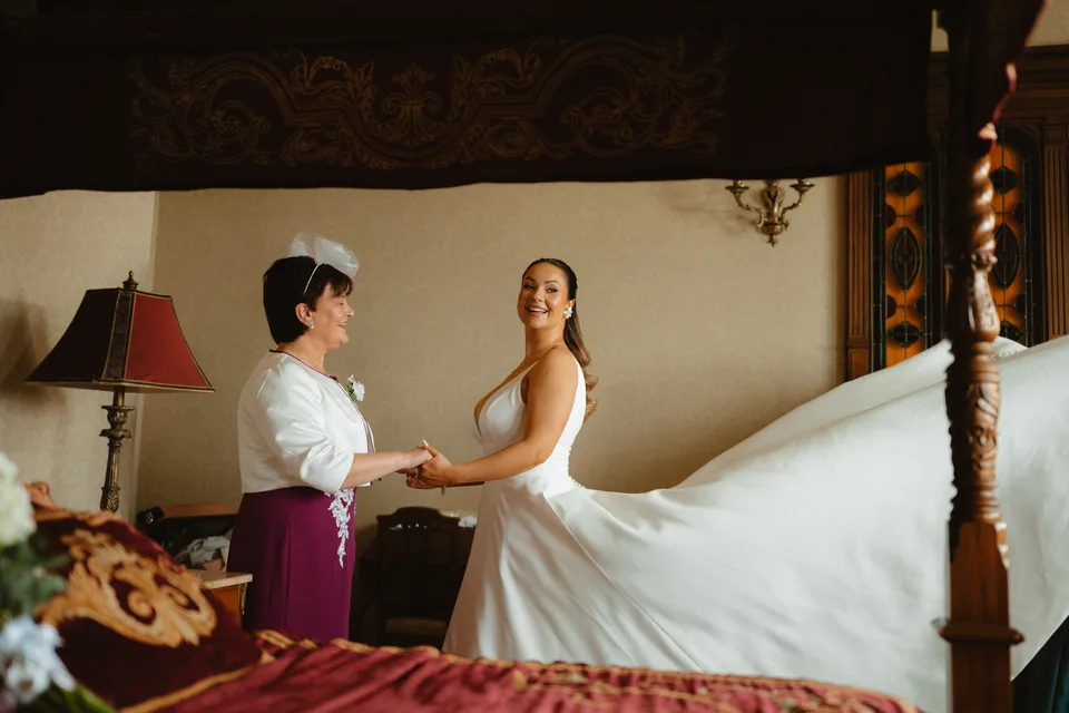 A helping hand with Lynsey’s wedding dress beside the four-poster bed.