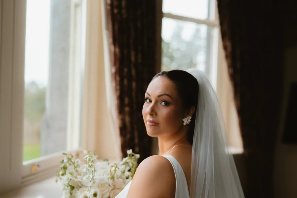 A close portrait of Lynsey in her veil beside the window.