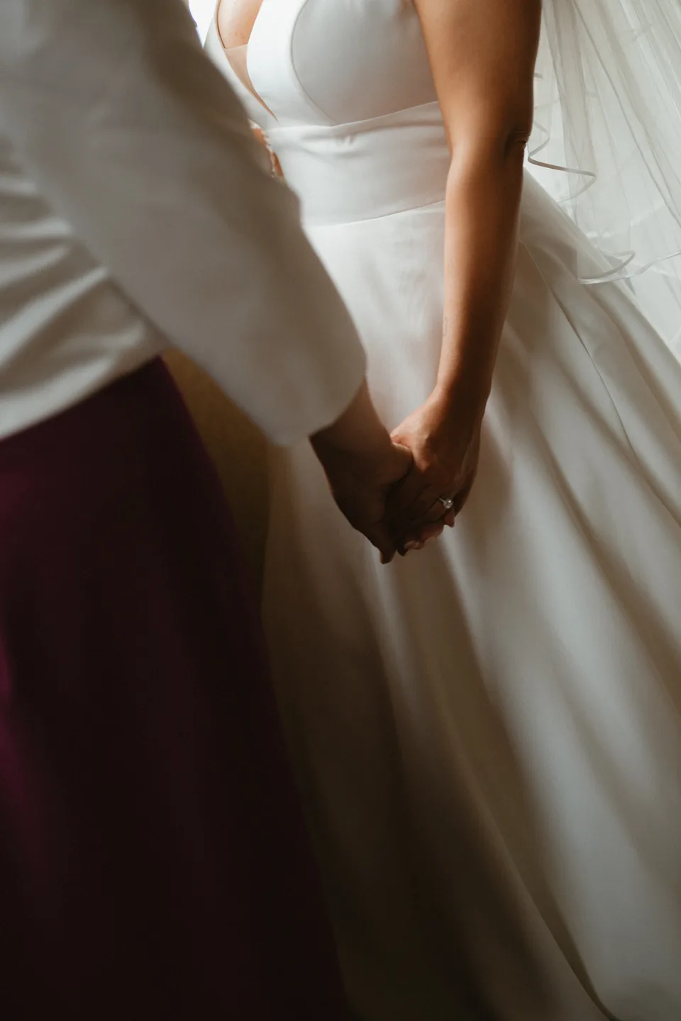 Hands fastening the back of Lynsey’s wedding dress.