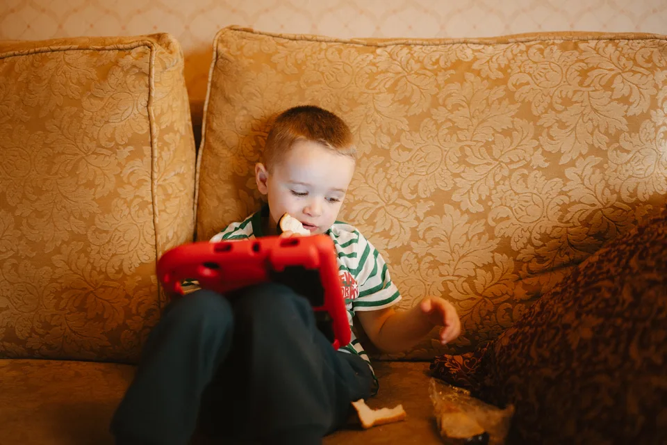 A young wedding guest using a tablet on the sofa during preparations.