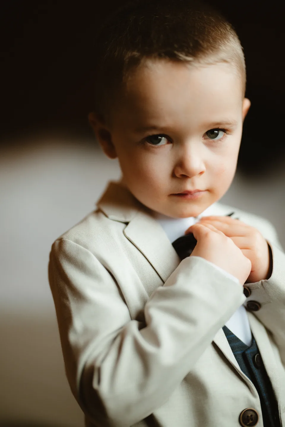 A young attendant adjusting his bow tie.
