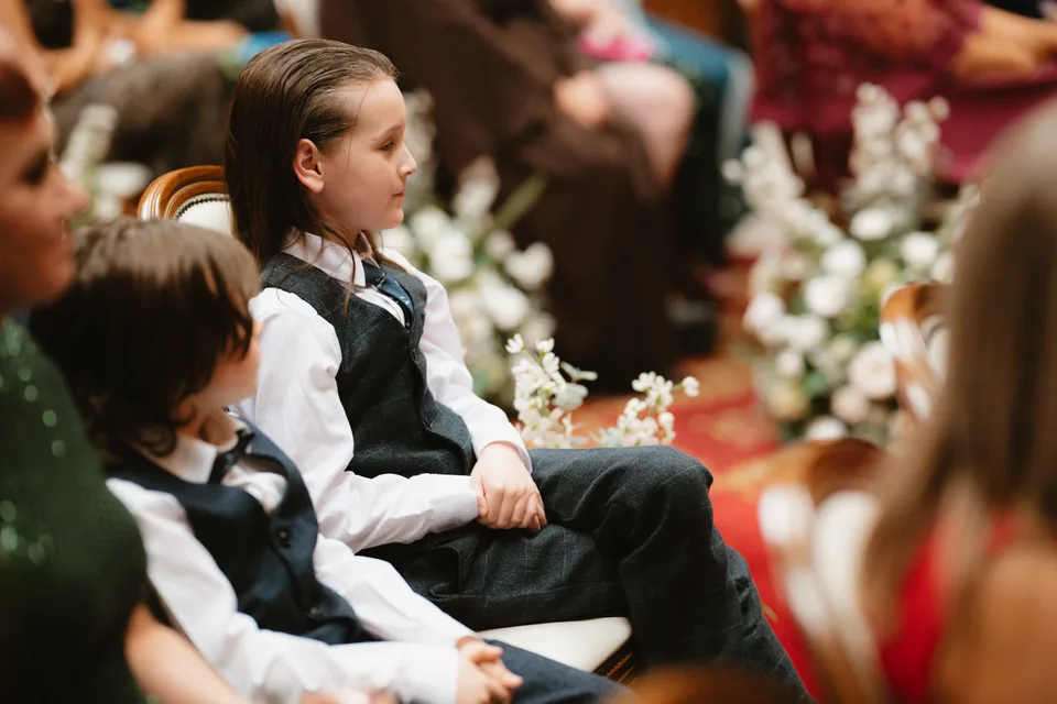 Young wedding guests watching from the ceremony seats.