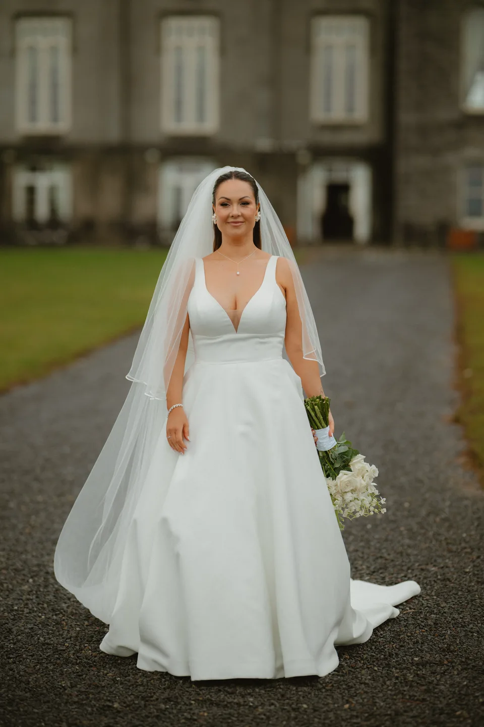 Lynsey holding her bouquet in front of the castle.