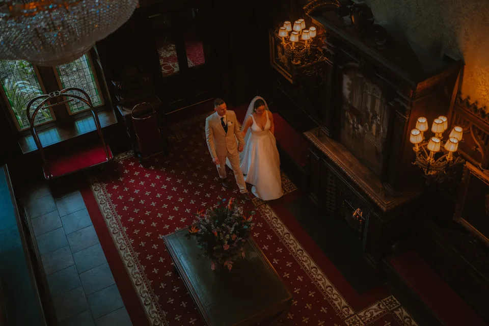 Lynsey and Jamie together beside the fireplace, seen from the staircase.