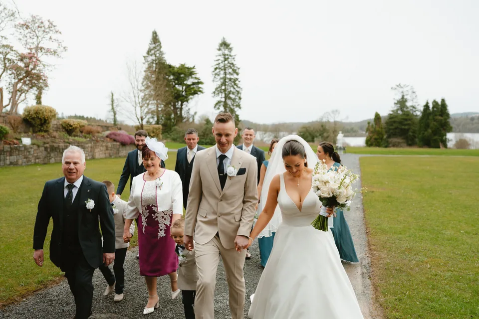Lynsey and Jamie walking across the lawn with family and friends.