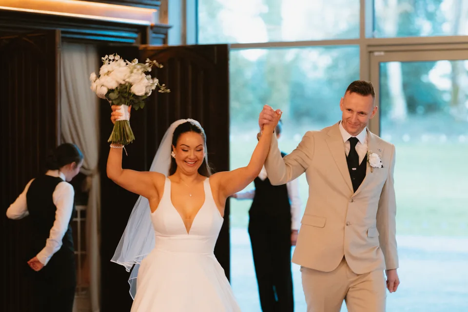 Lynsey and Jamie arriving at their reception with their hands raised.