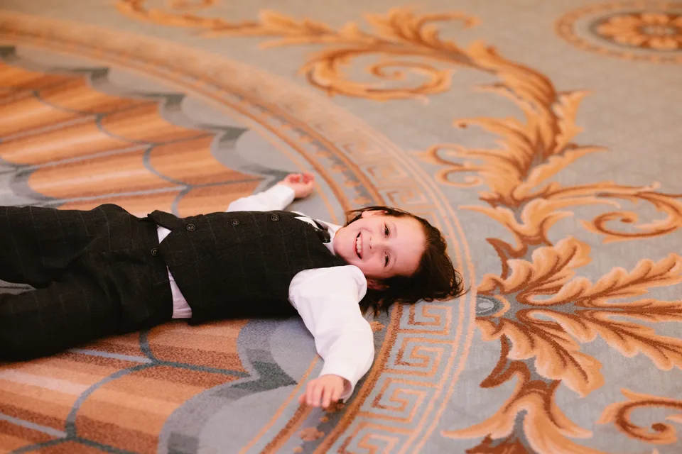 A young guest resting on the patterned carpet during the reception.