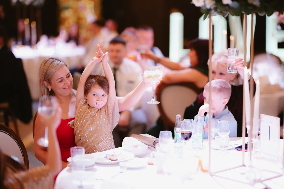 A young guest raising a glass at the wedding reception.