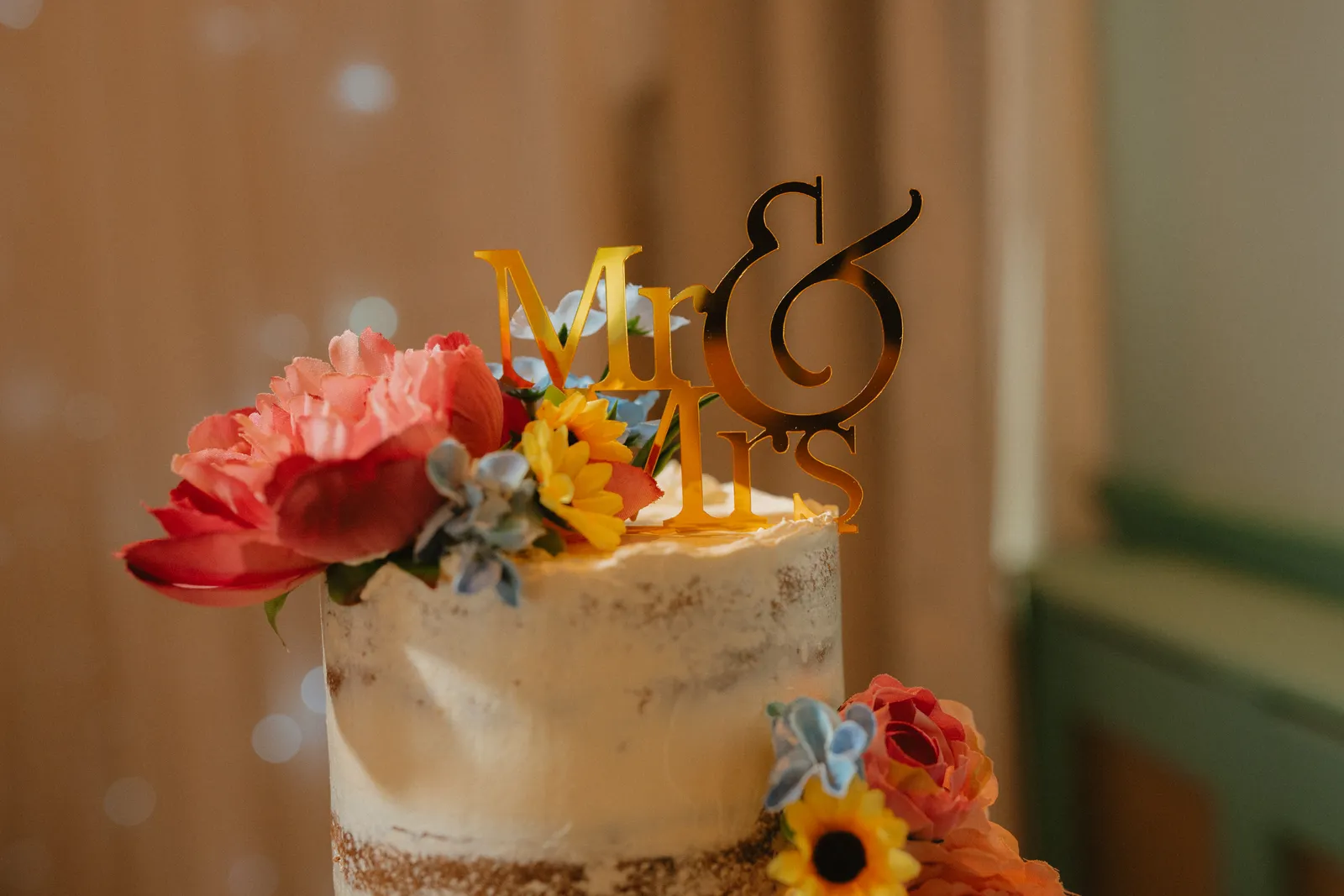 Wedding cake with colourful flowers and a gold topper