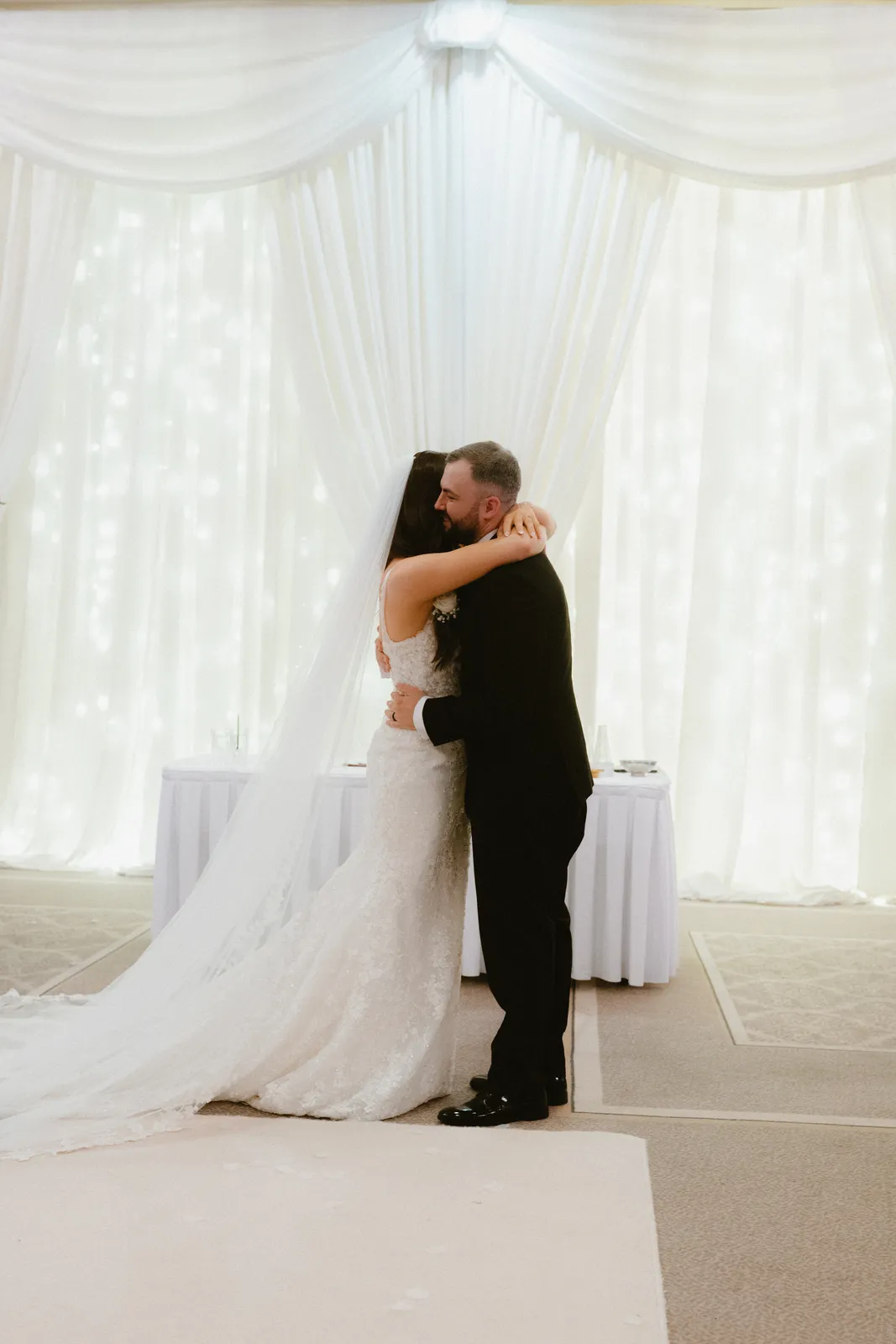 An embrace in front of the white ceremony drapes