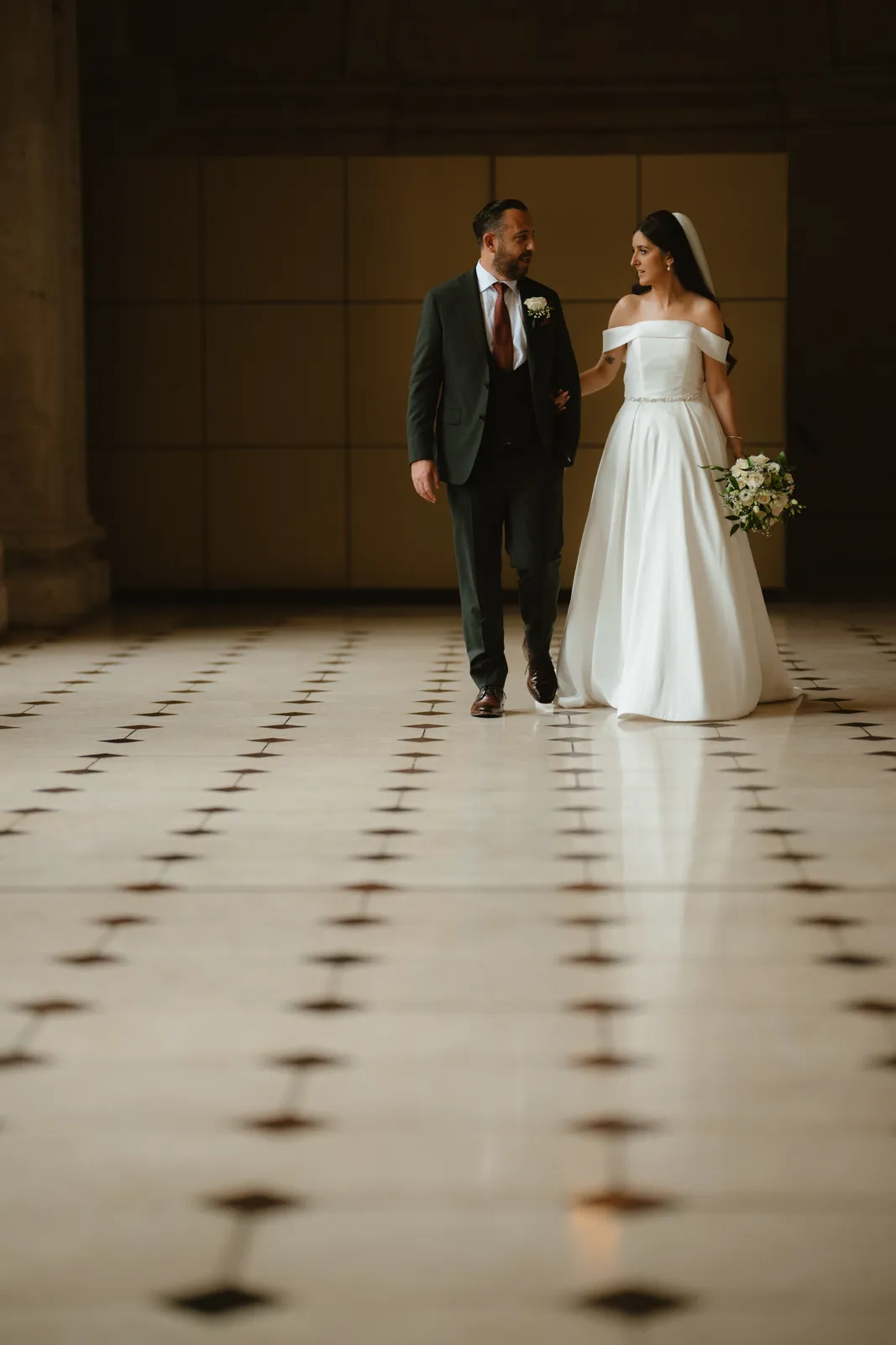 The couple cross the tiled floor