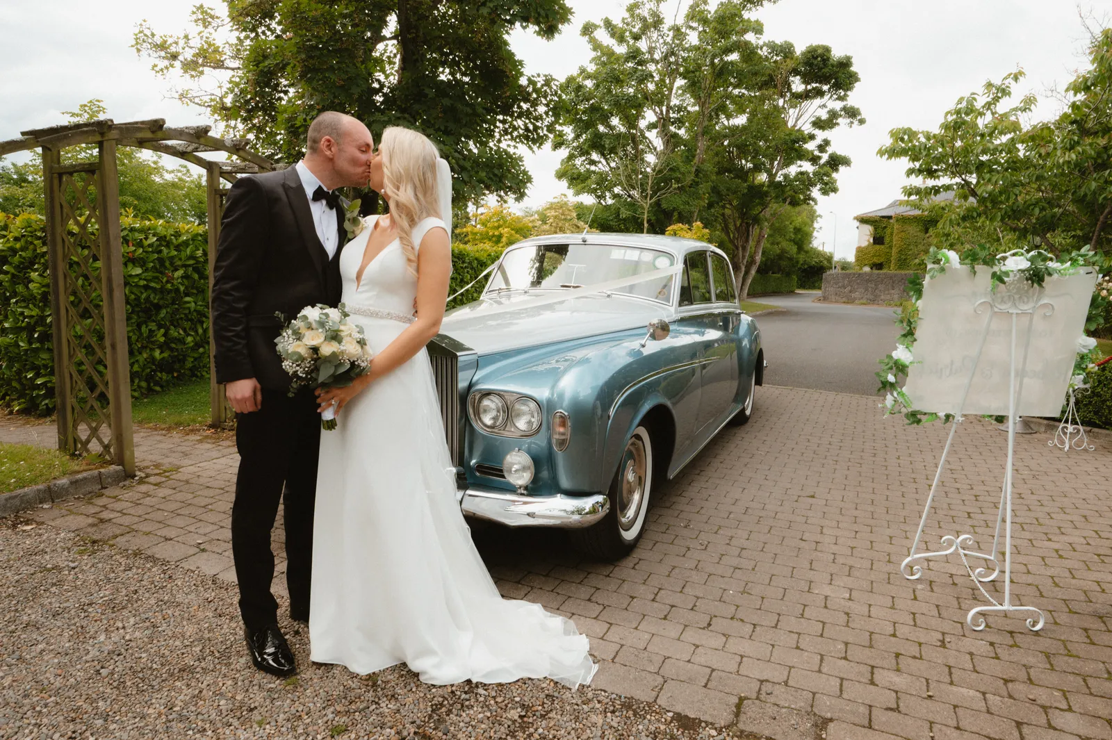 The couple beside a pale blue wedding car