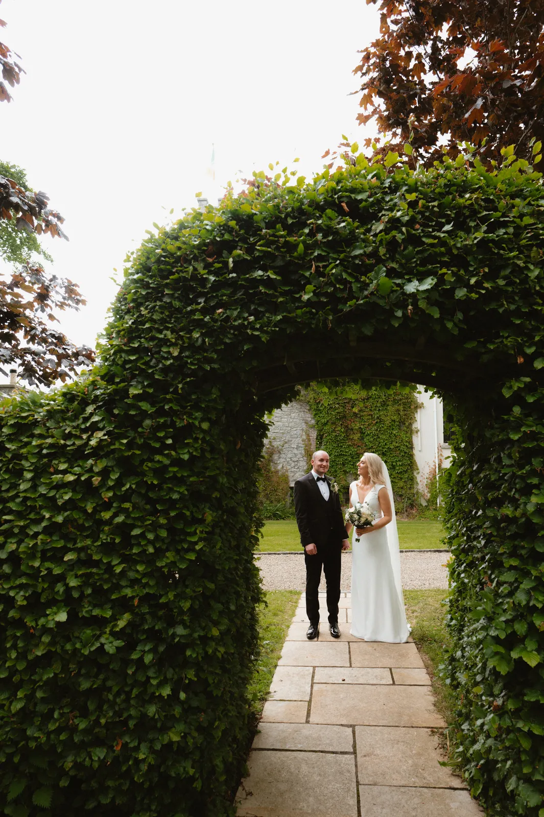 A leafy garden arch frames the couple