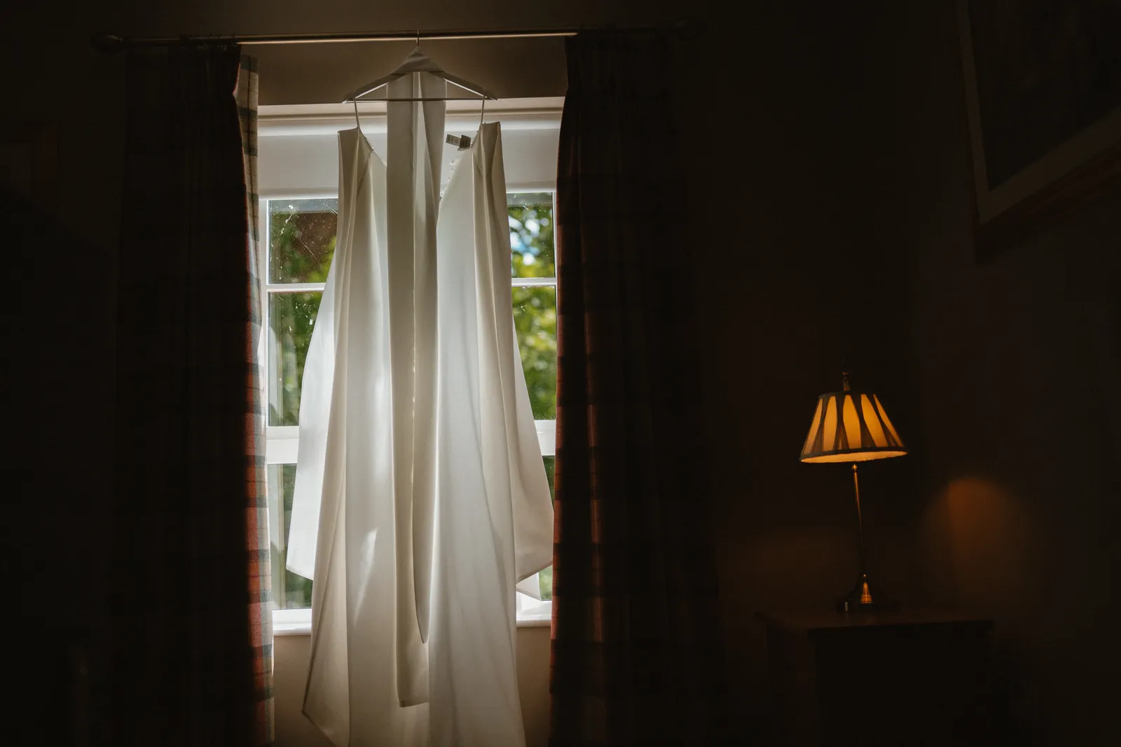 Roslyn’s wedding dress hanging beside a window