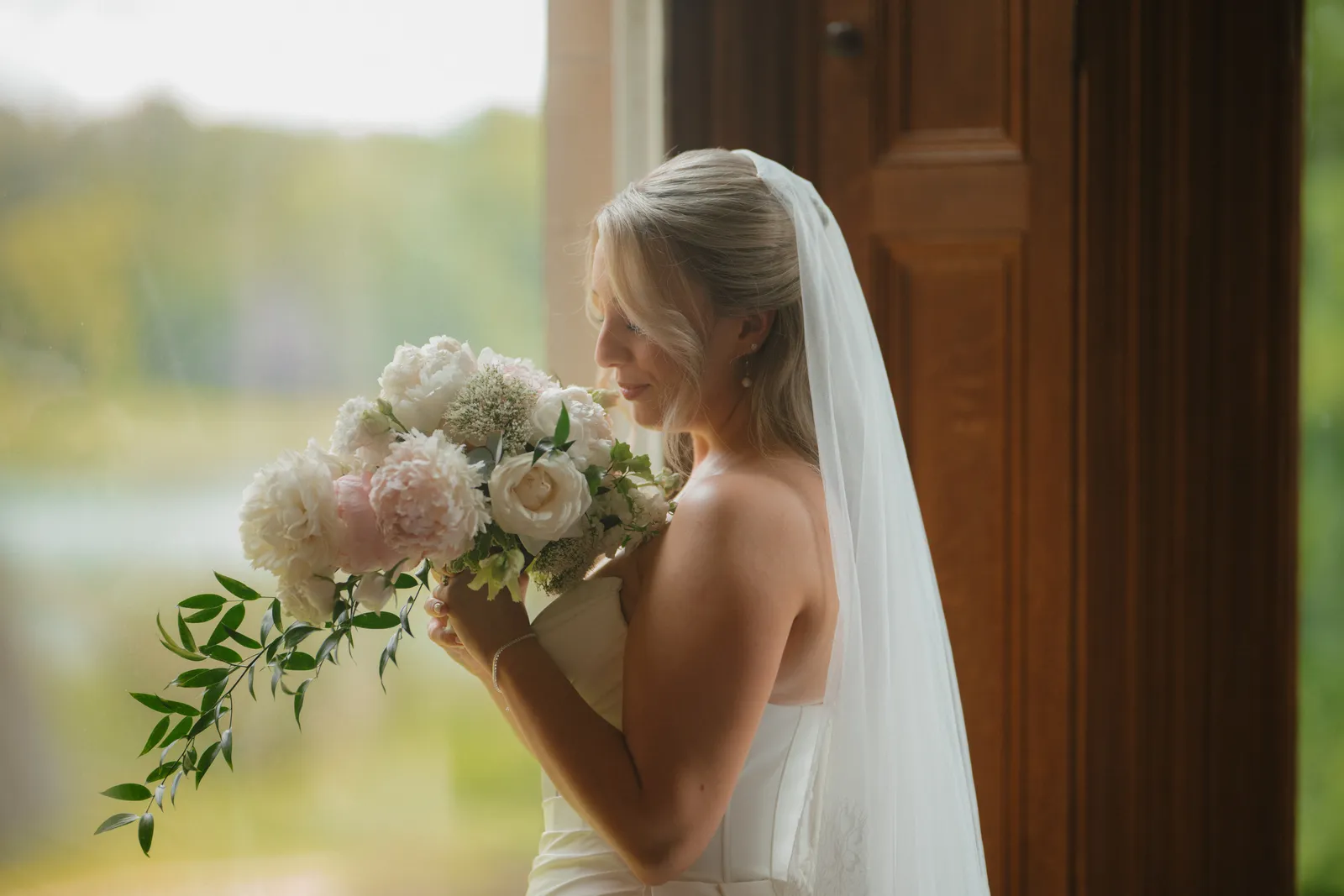 Roslyn holding her bouquet beside a window