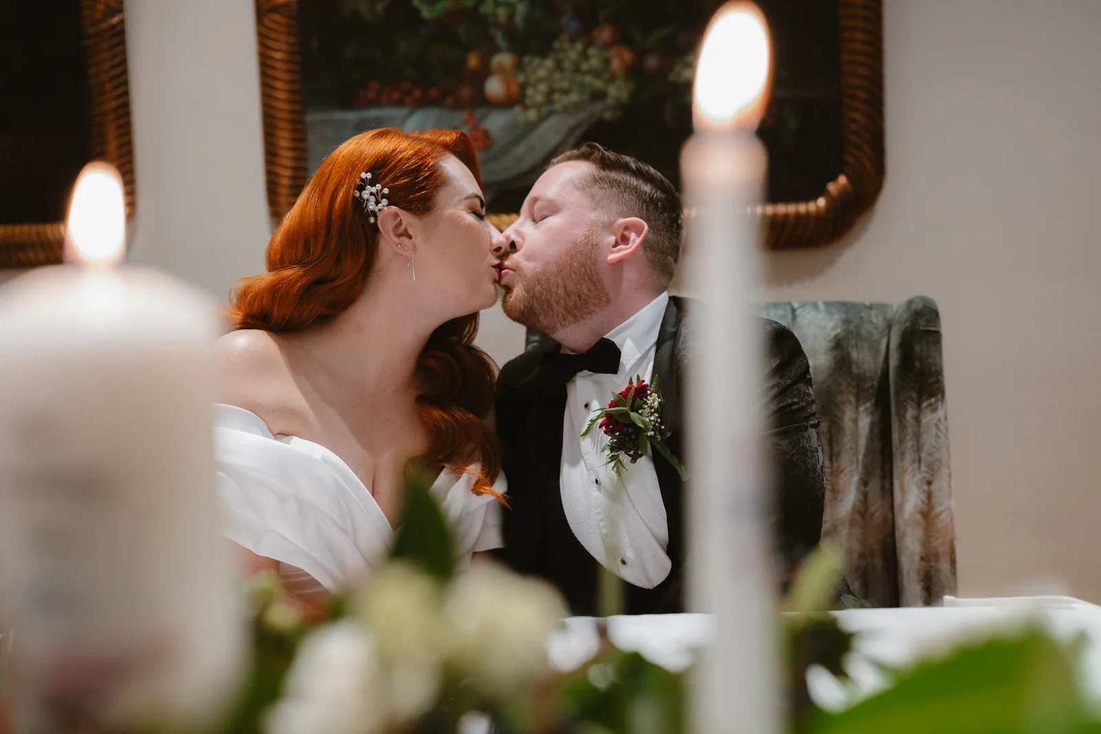 Sarah and Mark kissing beside the ceremony candles