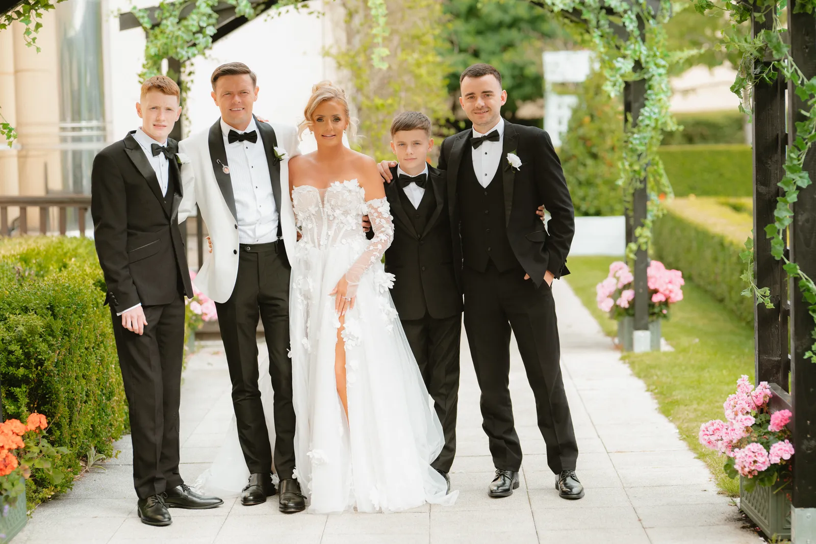 The couple with guests beneath a garden arch
