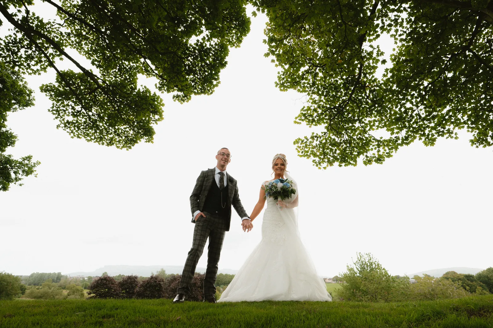 The couple holding hands beneath the tree