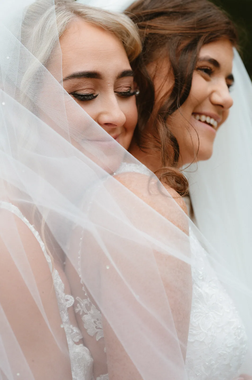 Zoe and Siobhra close together beneath the veil