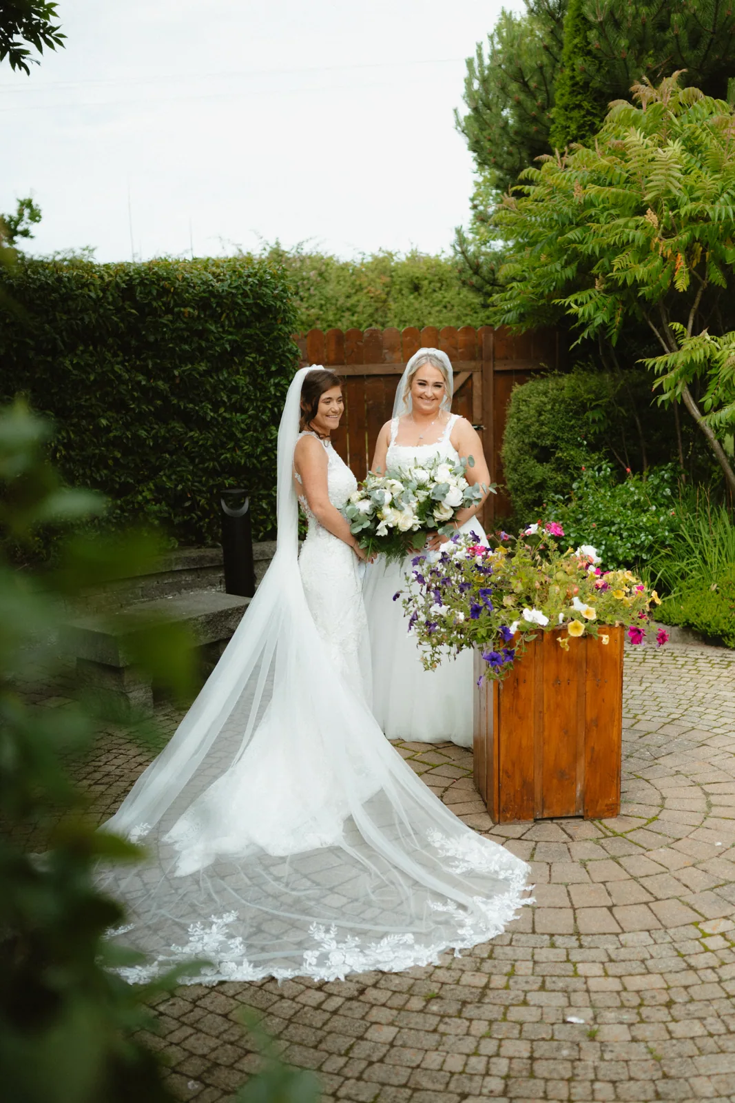 The couple together beside the garden flowers